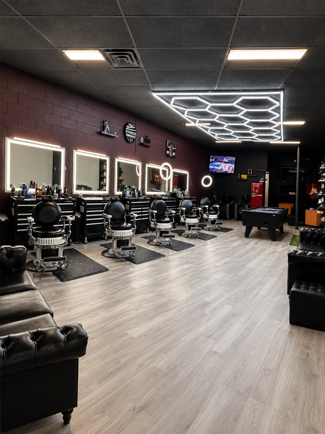 God Level barbershop interior with barber chairs, black leather sofas, a pool table and geometric ceiling lights