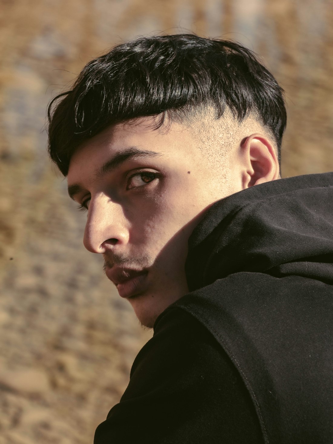 Man with a textured crop, straight fringe and faded sides, looking over his shoulder