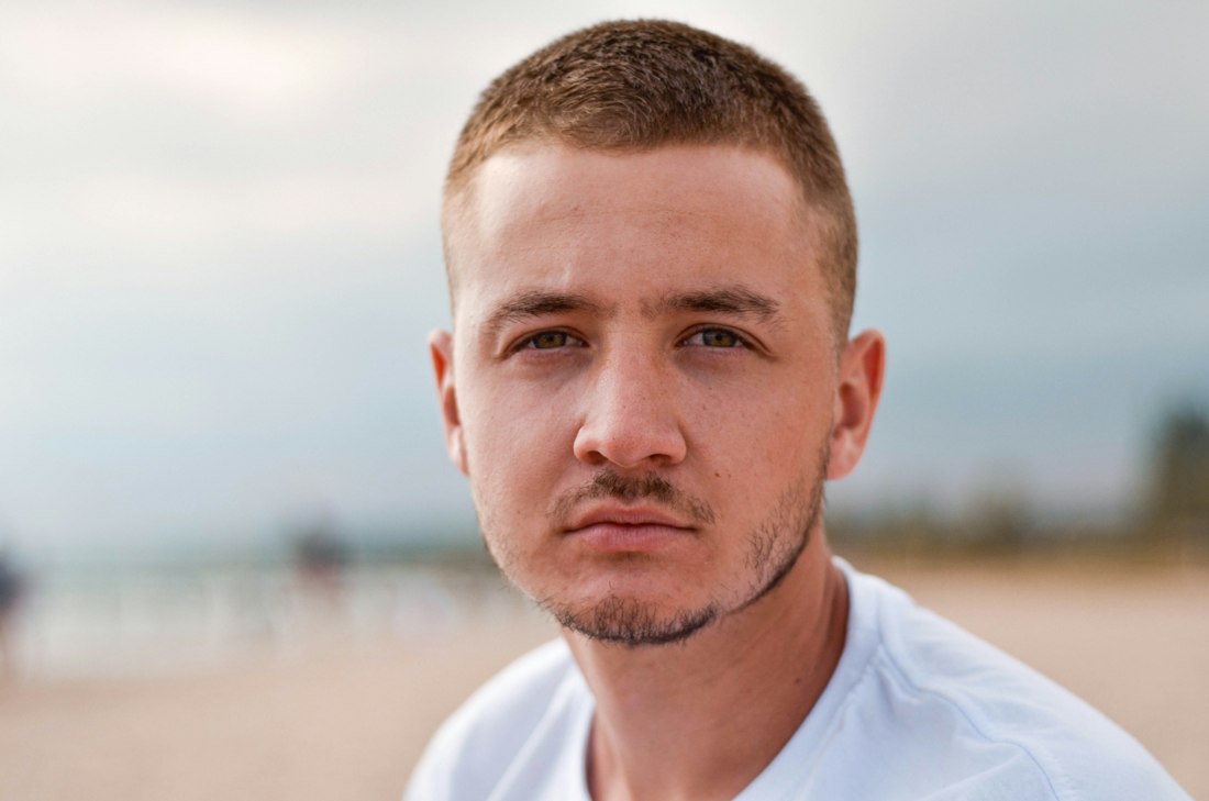 Man with a short crew cut on a beach