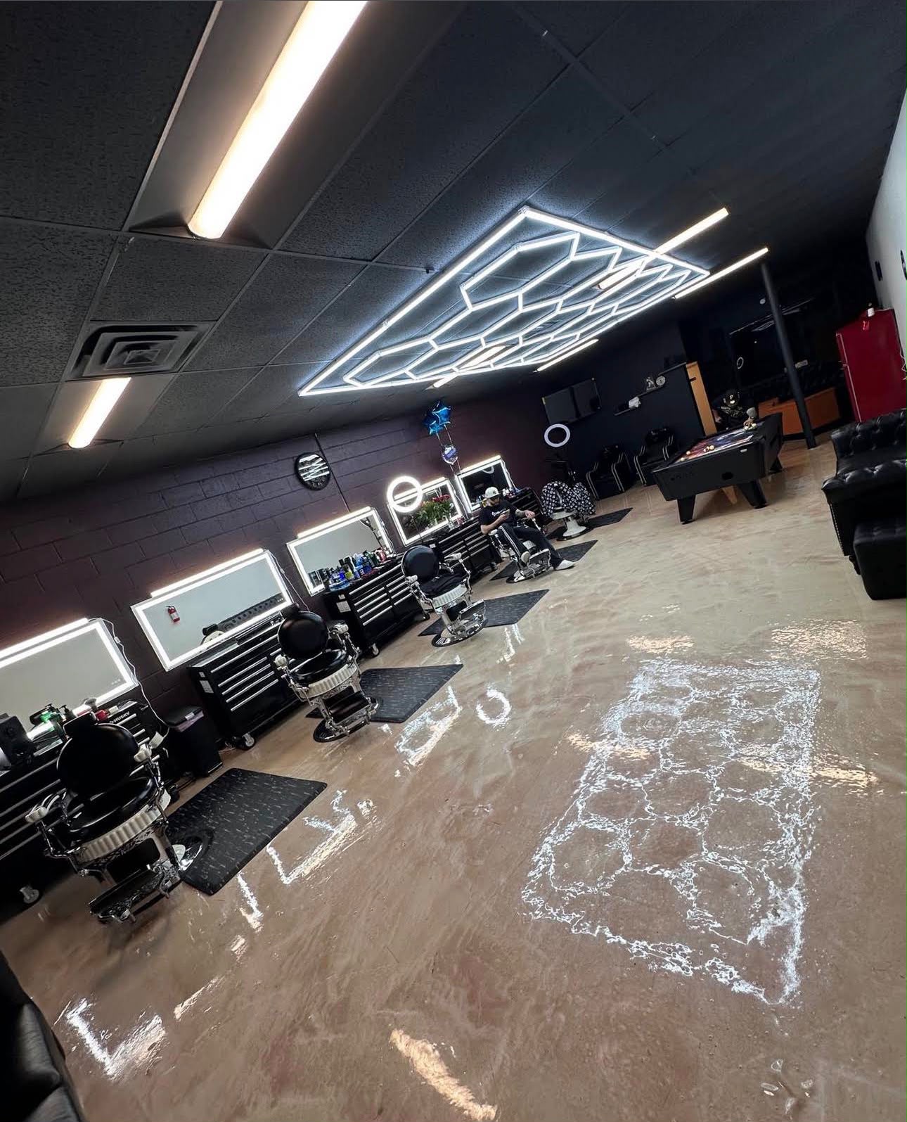 Interior of God Level Barbershop with geometric lights, chairs and pool table